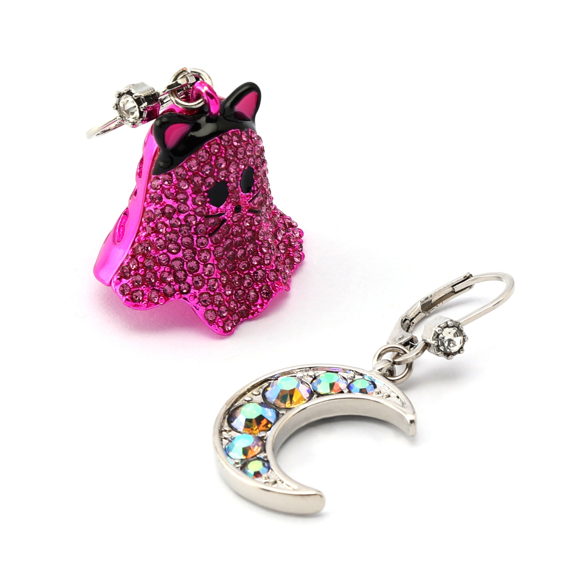 Pink ghost-shaped keychain with black hair and a silver crescent moon-shaped keychain with multicolored stones on a white background.