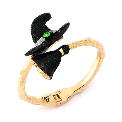 Gold bracelet with black witch hats and a green gemstone on a white background