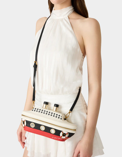 Person wearing a white dress with a unique bag featuring a ship design.