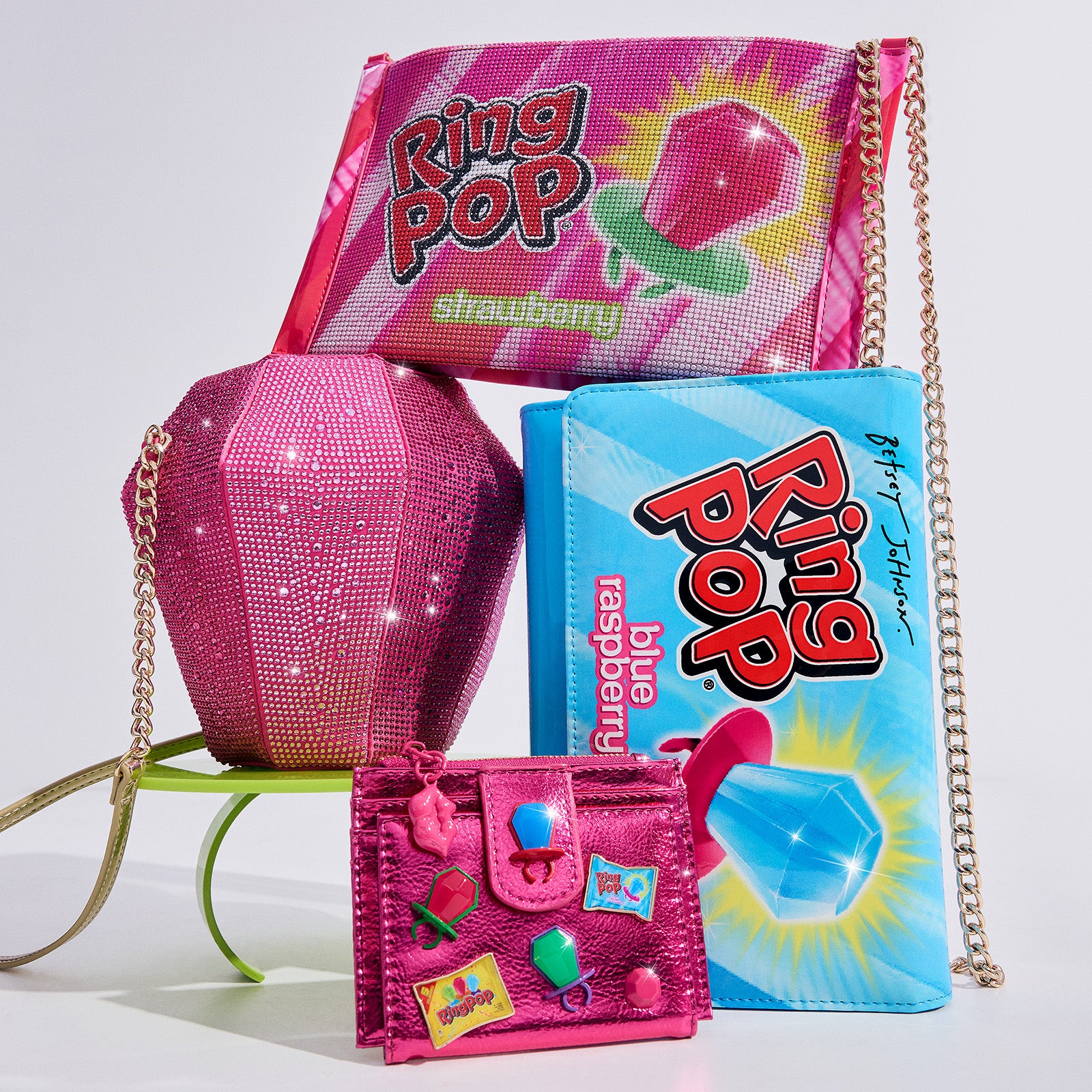 Pink glittery handbag, small wallet, and Ring Pop candy packages on a white background