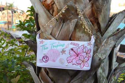Handbag with tropical design and chain strap against a palm tree background