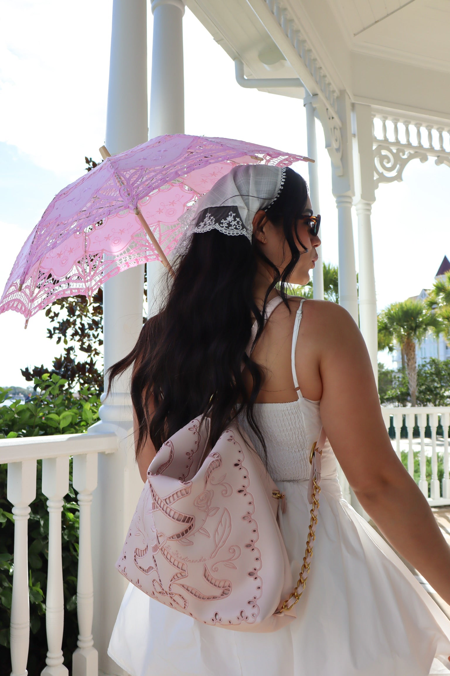 Woman holding a pink lace parasol on a balcony