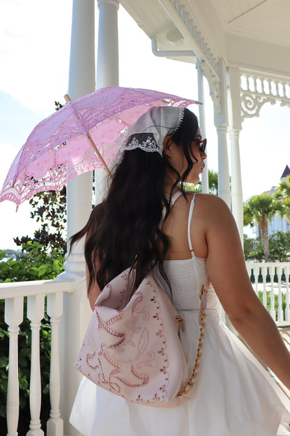 Woman holding a pink lace parasol on a balcony
