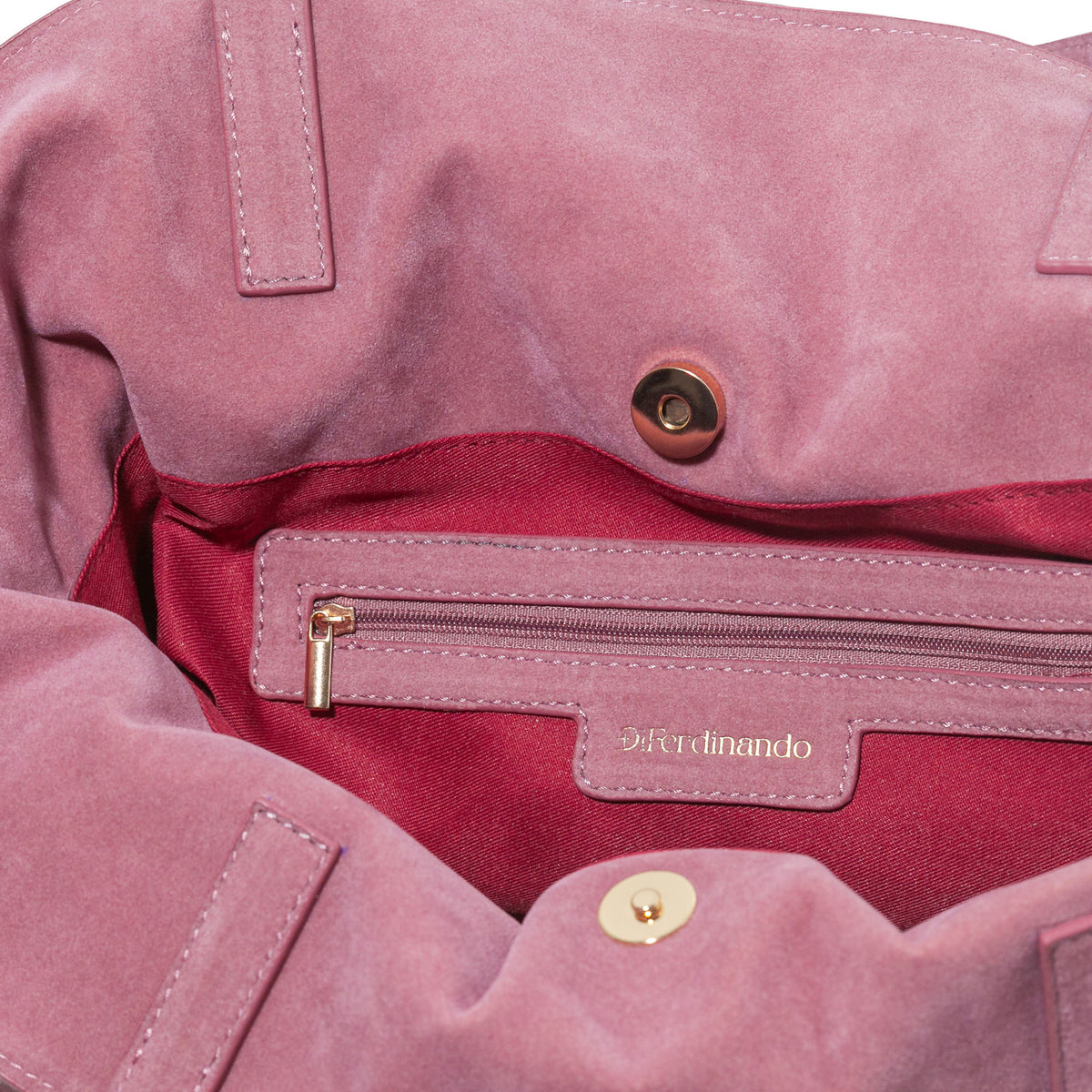 Close-up of a pink bag with gold zipper and button details, featuring the brand 'Ferdinando'.