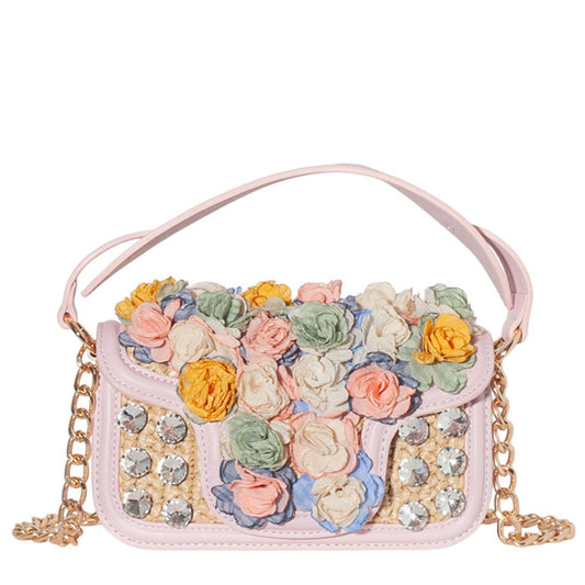 Pink handbag with floral embellishments and a chain strap on a white background